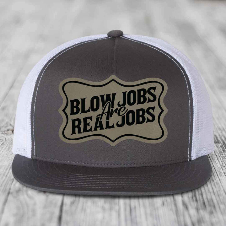 Grey trucker hat with white mesh back and black embroidered patch reading &
