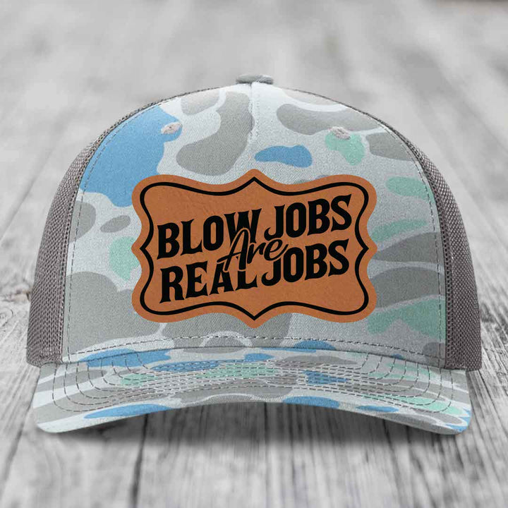 Camouflage trucker hat with brown leather patch reading &