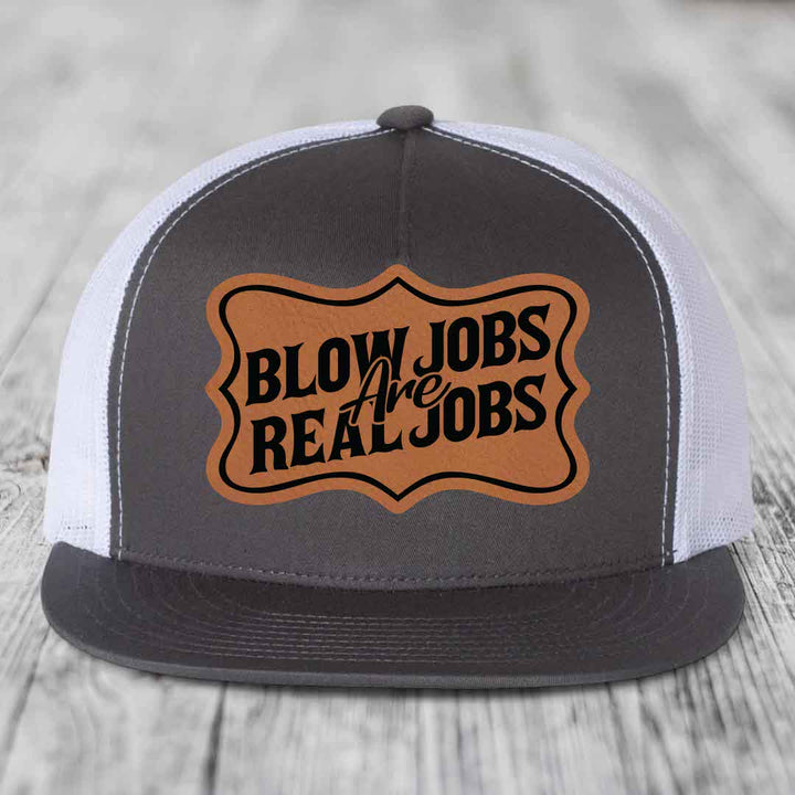Grey front panel trucker hat with brown leather patch reading &