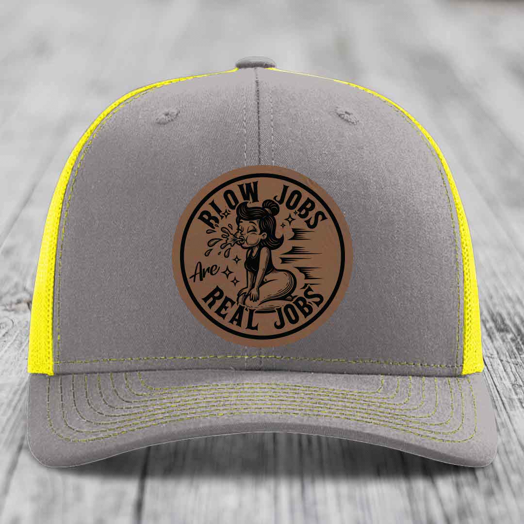 Grey trucker hat with yellow mesh panels and a brown leatherette patch reading &
