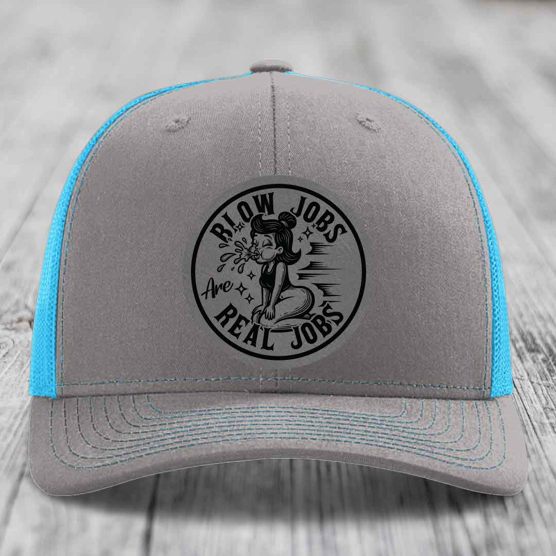 Grey trucker hat with blue mesh back and black circular patch reading &