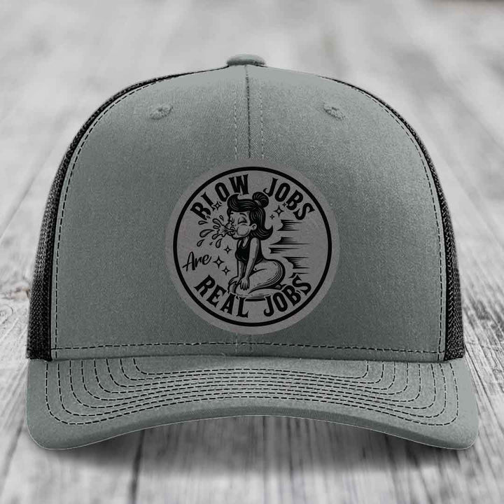 Grey trucker hat with black embroidered patch reading &