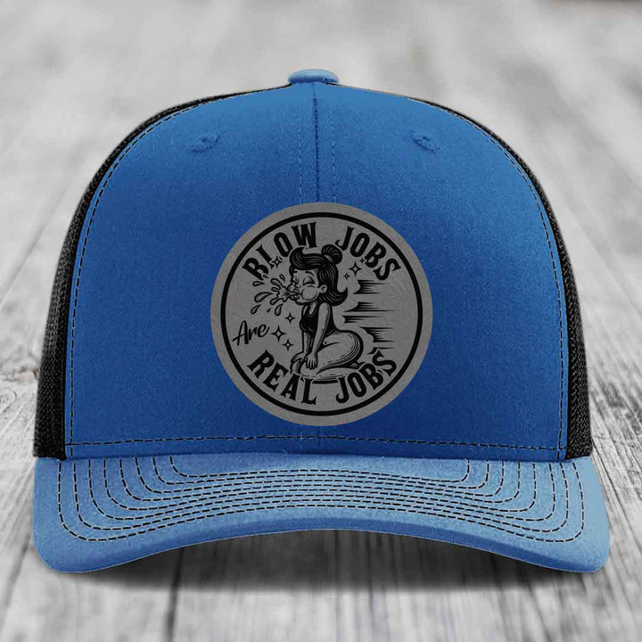Blue trucker hat with black mesh back and gray circular patch reading &