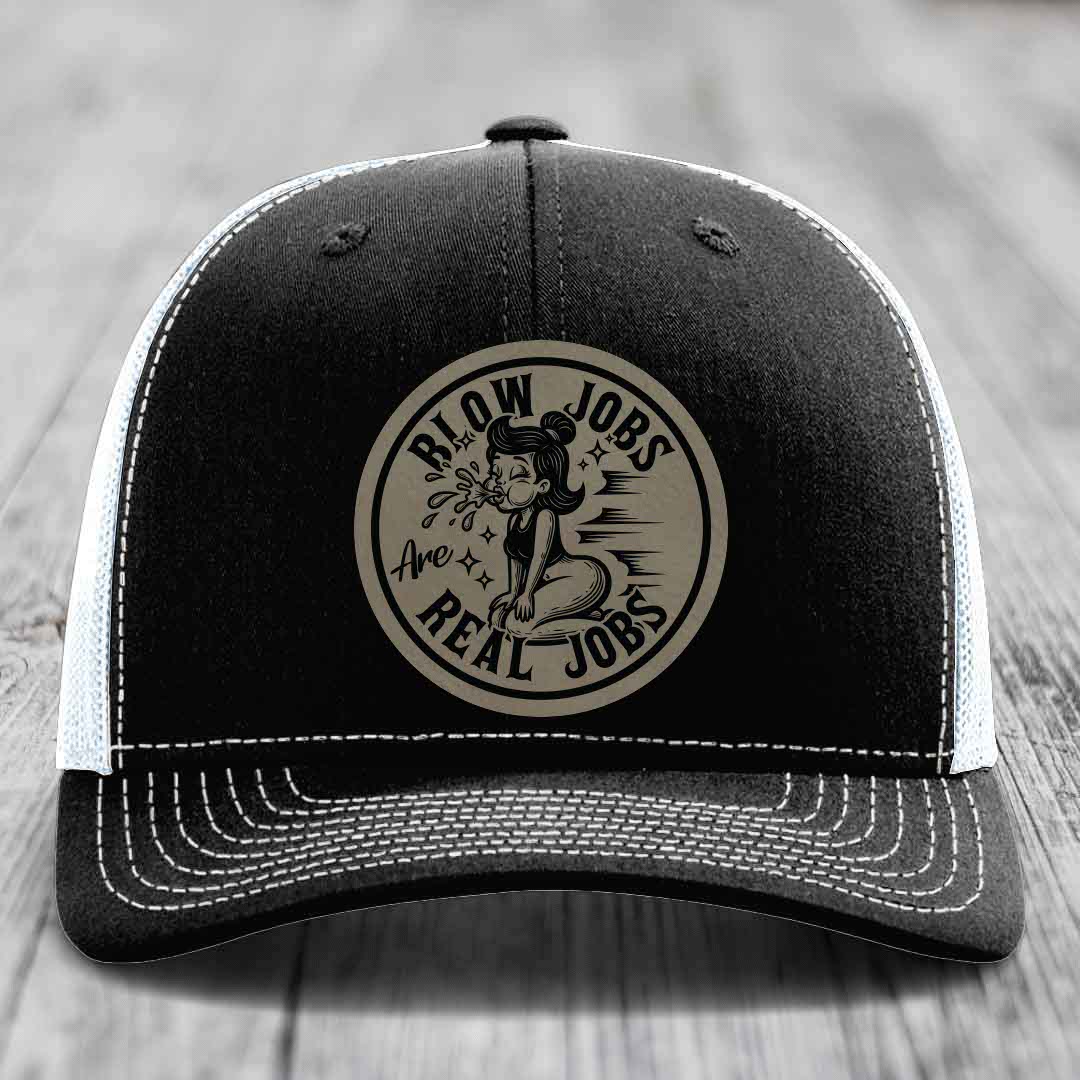 Black trucker hat with white mesh back and stitching, featuring a circular beige patch with black text and illustration.
