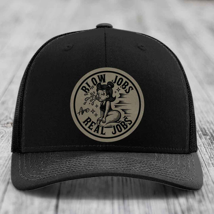 Black trucker hat with circular beige patch featuring cartoon woman and text &
