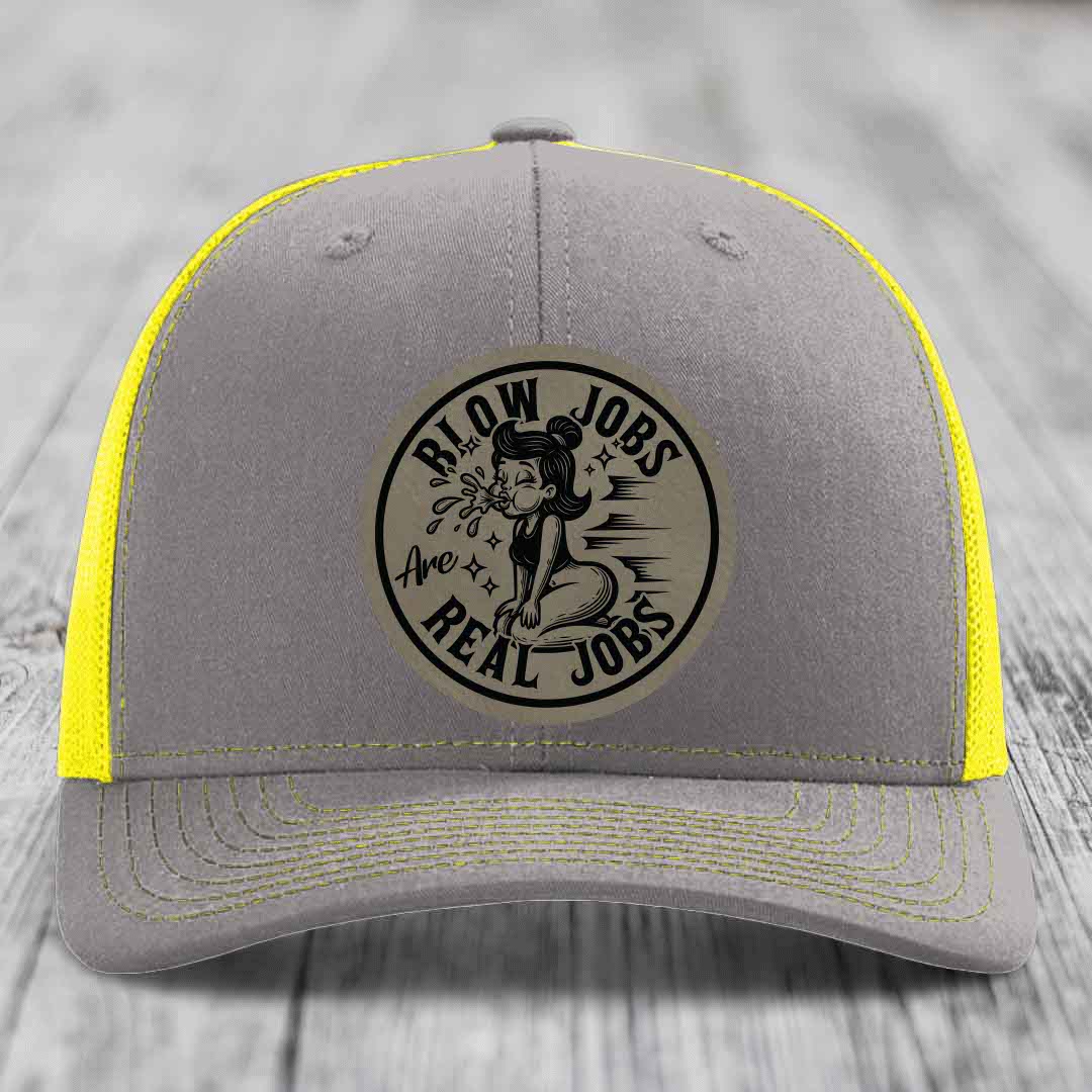 Grey trucker hat with yellow mesh and stitching, featuring a circular patch that reads &