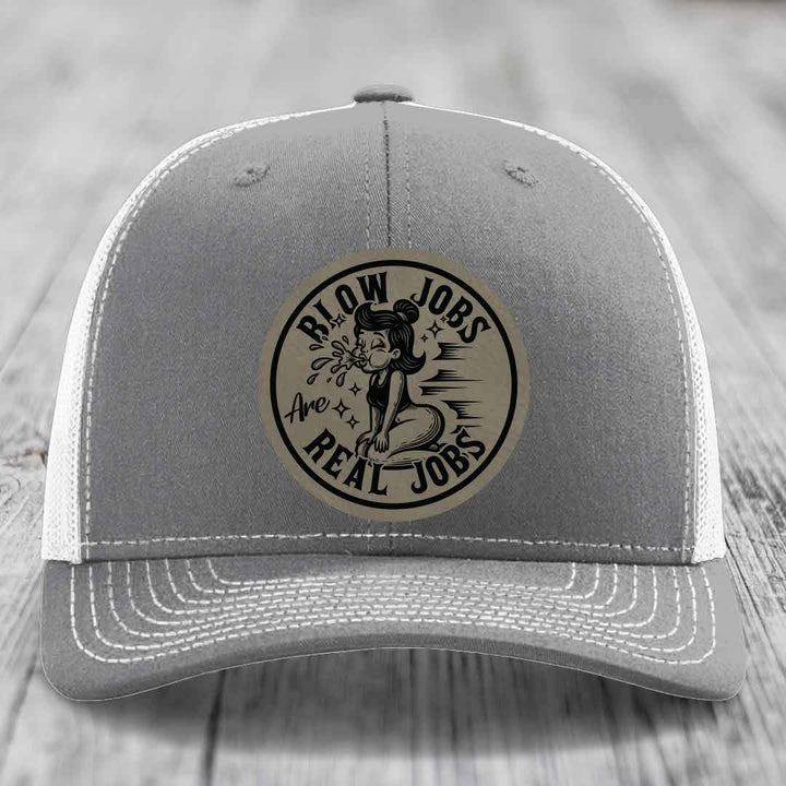 Grey trucker hat with white mesh back and embroidered circular patch reading &