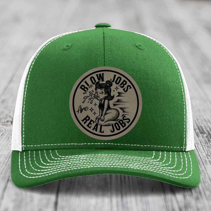 Green trucker hat with white mesh back and stitching, featuring a circular beige patch with black text reading &