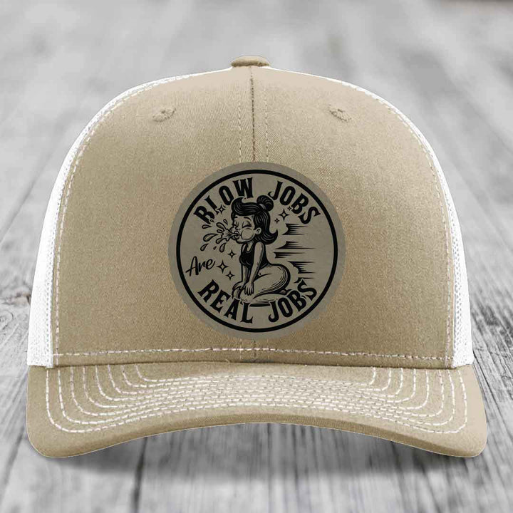 Tan trucker hat with black circular patch reading &