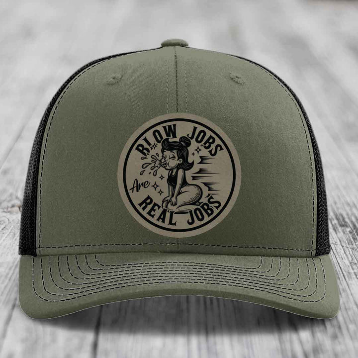 Olive green trucker hat with black mesh back and a circular beige leatherette patch that says &