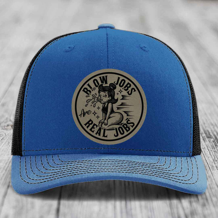 Blue trucker hat with black mesh back and beige circular patch reading &