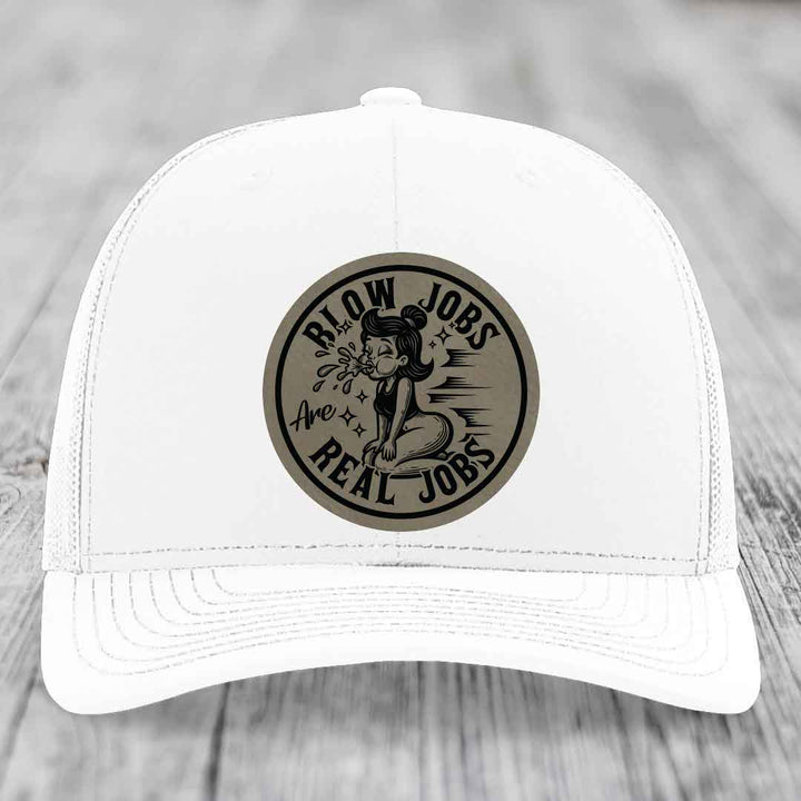 White trucker hat with a circular leatherette patch featuring text and illustration.