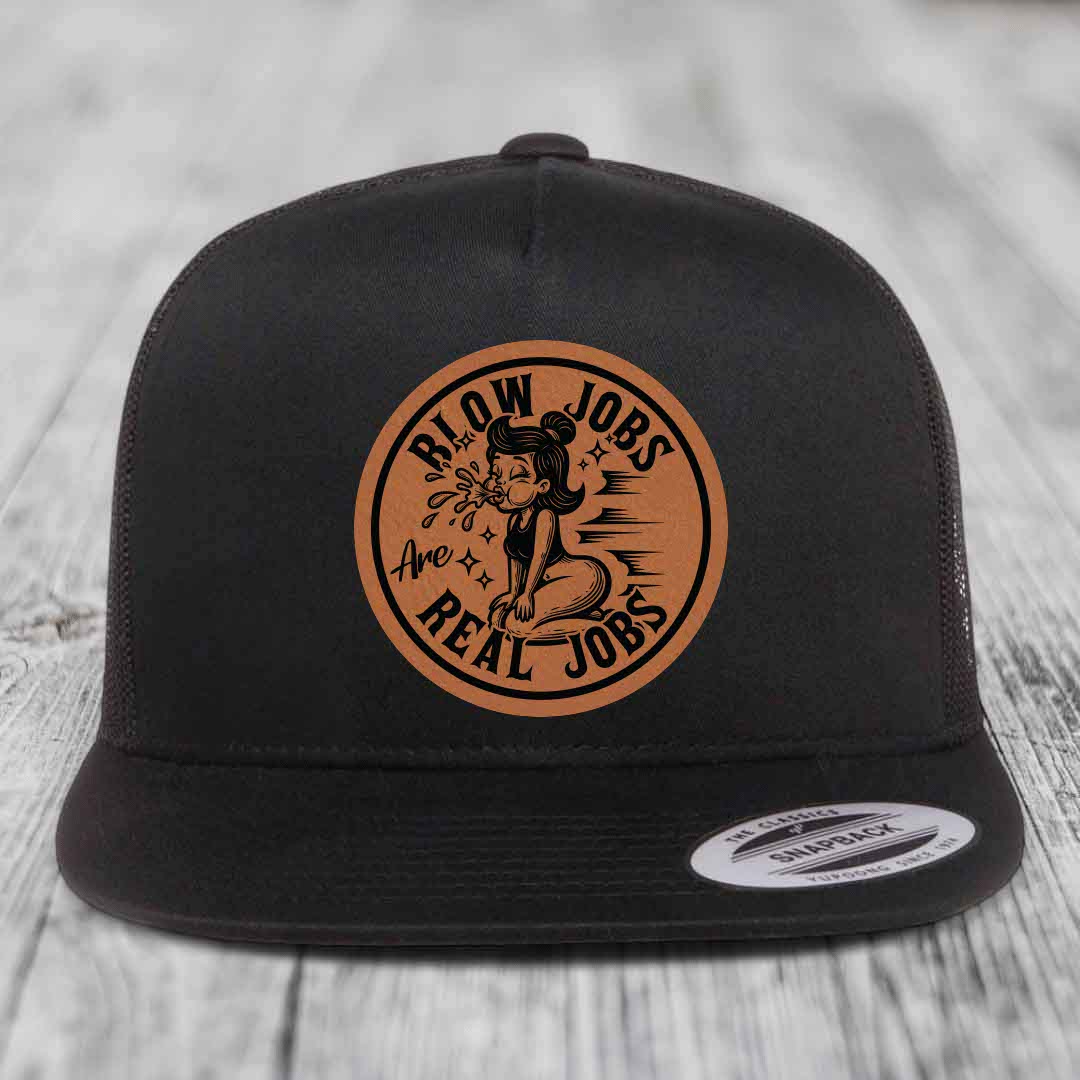 Black snapback hat with brown circular leather patch featuring cartoon woman and text &