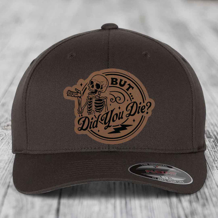 Dark brown Flexfit hat with a circular leather patch featuring a skeleton and the text &