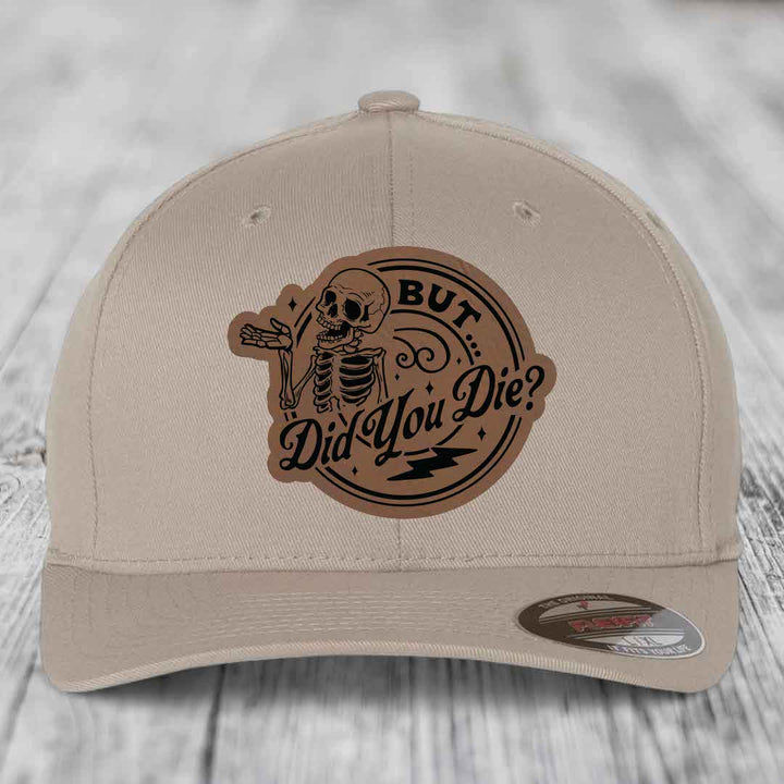 Beige baseball cap with a brown leatherette patch featuring a skeleton and the text &