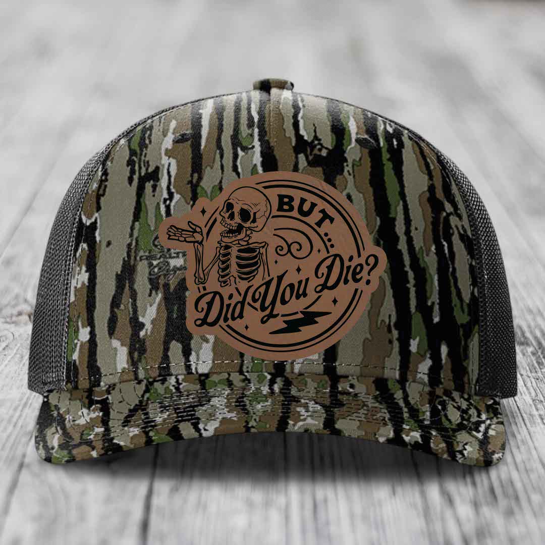 Camouflage trucker hat with brown leather patch featuring skeleton and text &