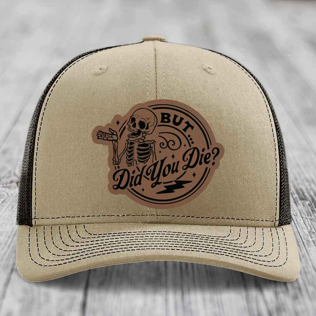Beige trucker hat with brown leather patch featuring skeleton and text &