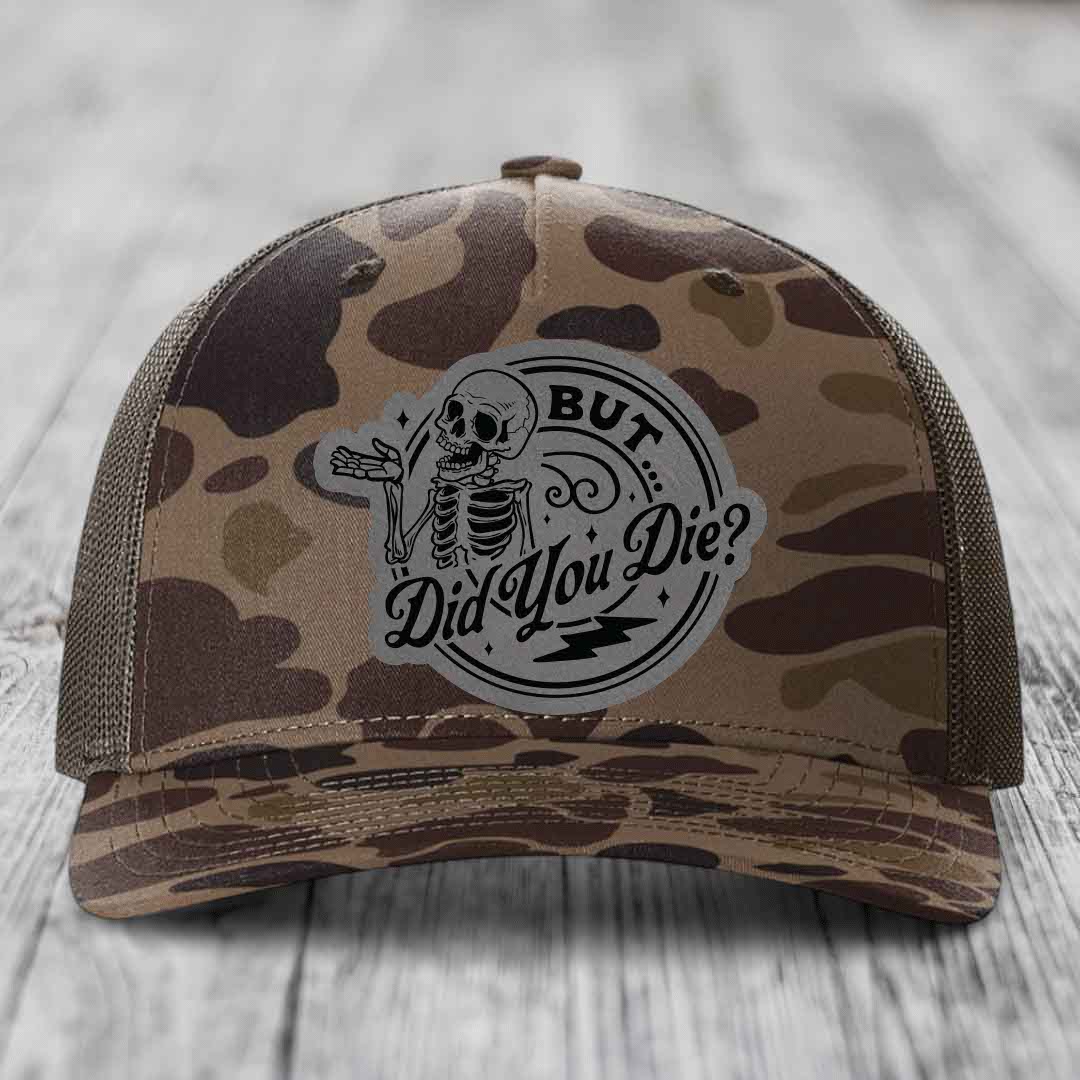 Camouflage trucker hat with a skeleton patch that reads &