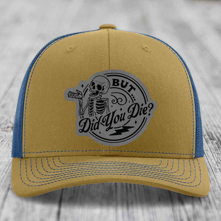 Tan and blue trucker hat with a skeleton graphic and text reading &
