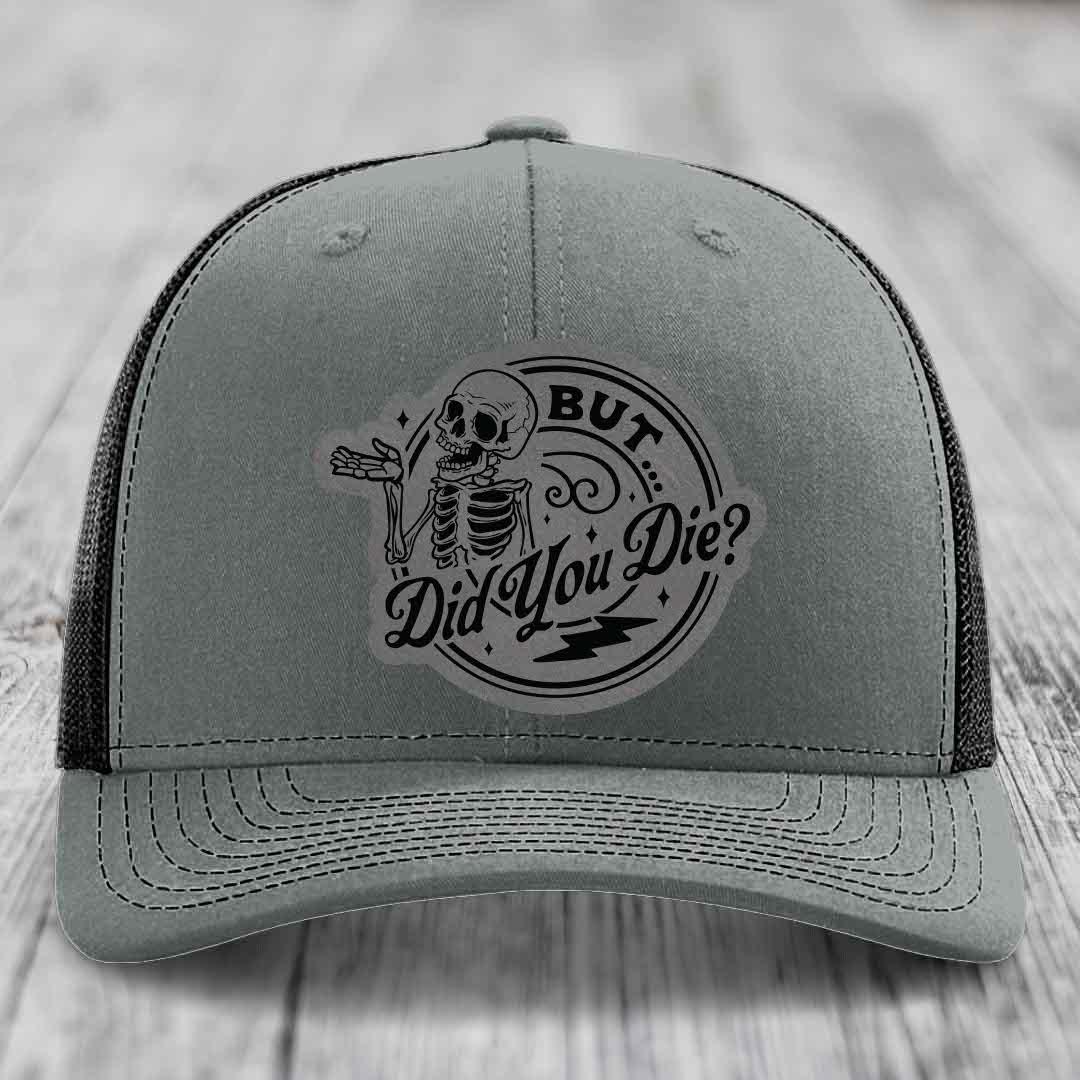 Grey trucker hat with black embroidered patch of skeleton and text &