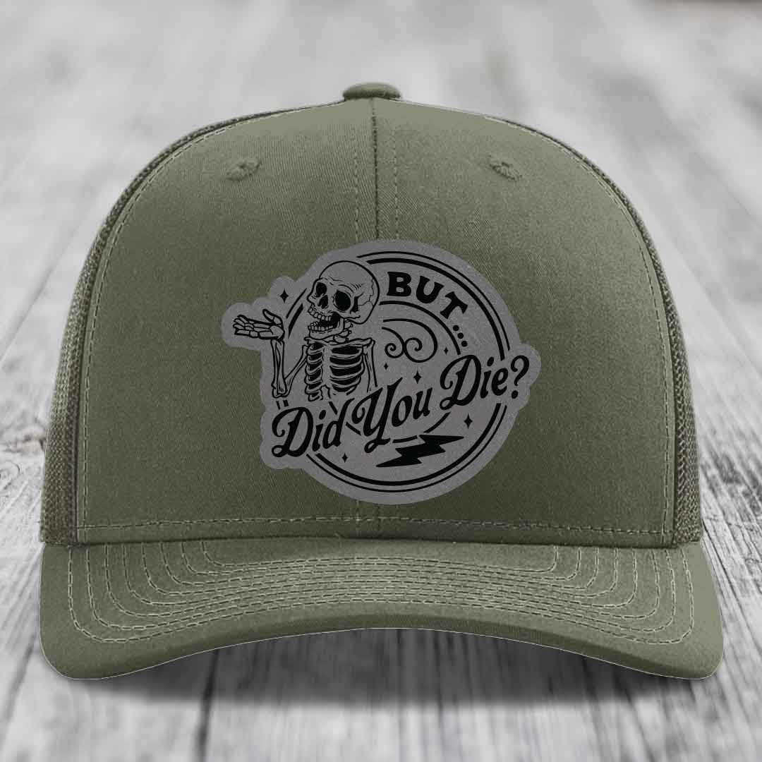 Olive green trucker hat with a circular patch featuring a skeleton and the text &
