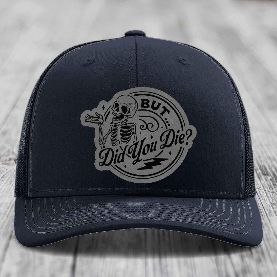 Dark blue trucker hat with a grey circular patch featuring a skeleton and the text &