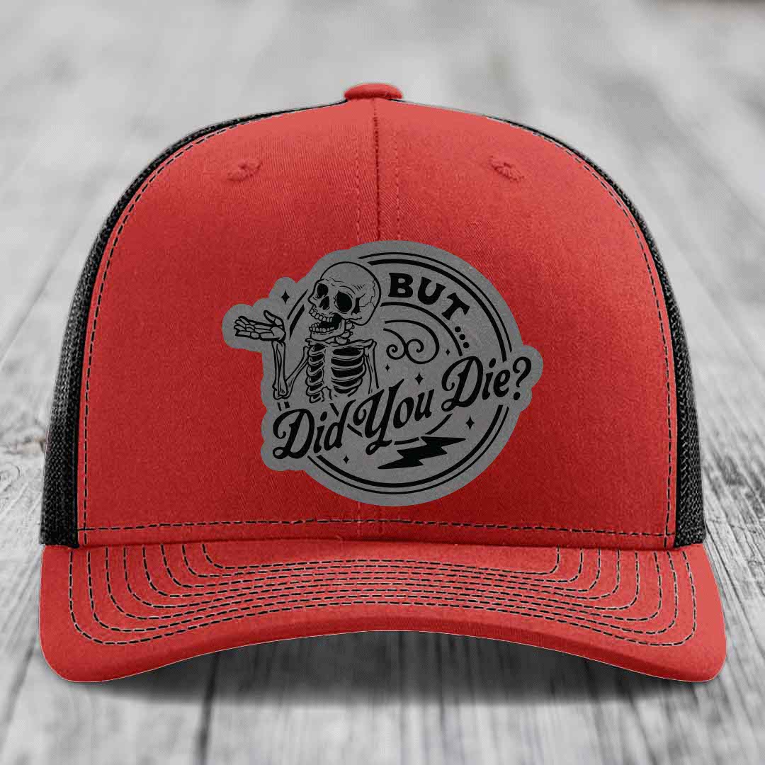 Red trucker hat with black mesh back and gray circular patch featuring a skeleton and text &