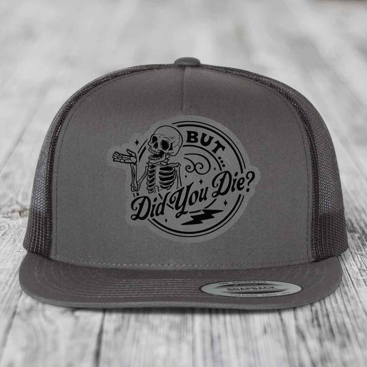 Grey trucker hat with black skeleton patch reading &