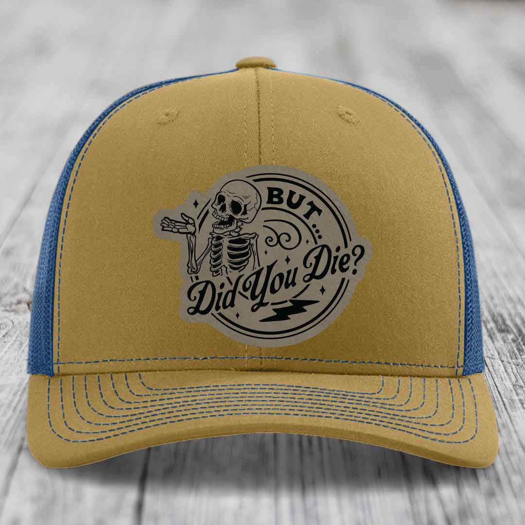 Tan and blue trucker hat with a skeleton graphic and text reading &