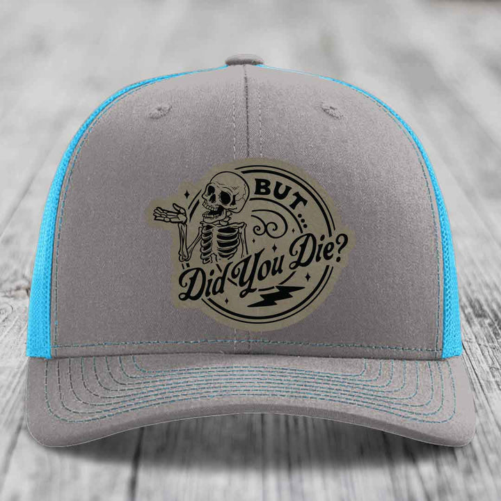 Grey trucker hat with blue mesh sides and a skull patch that reads &