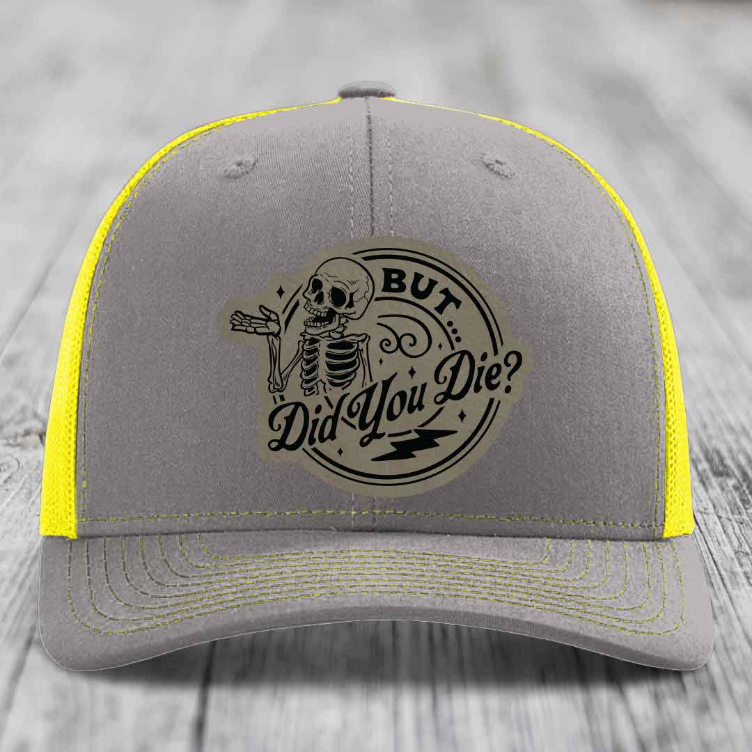 Grey trucker hat with yellow mesh and stitching, featuring a circular &