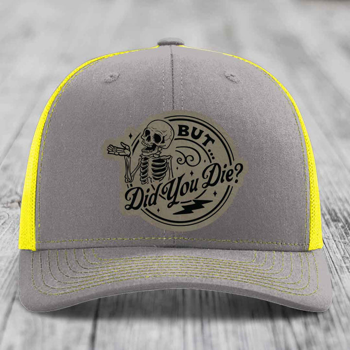 Grey trucker hat with yellow mesh and stitching, featuring a circular &