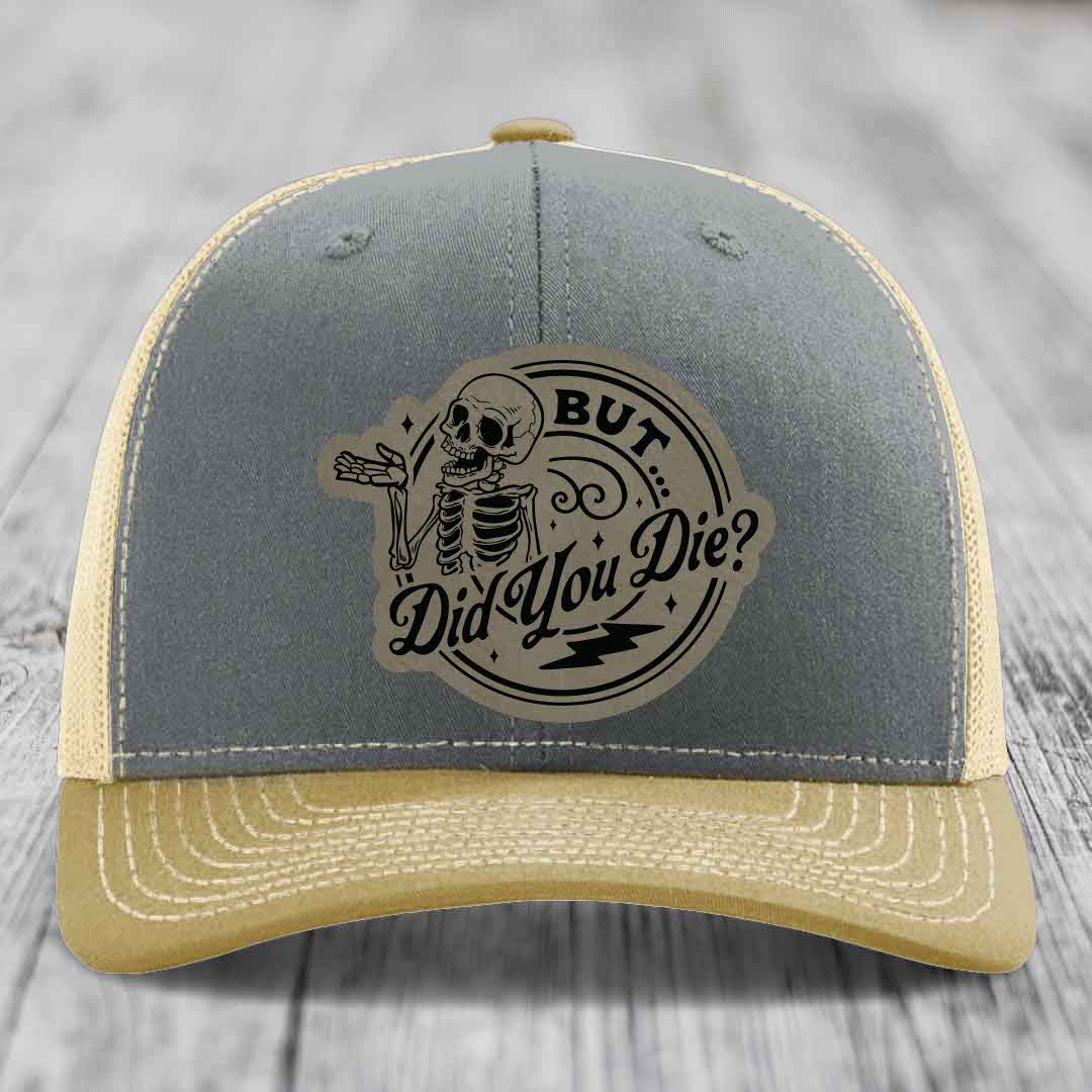 Grey and beige trucker hat with a skeleton patch that reads &