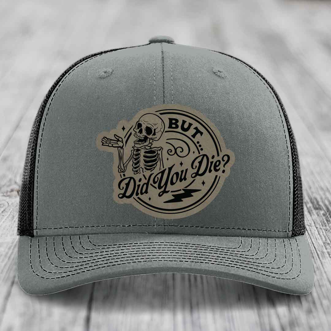 Grey trucker hat with a circular patch featuring a skeleton and the text &