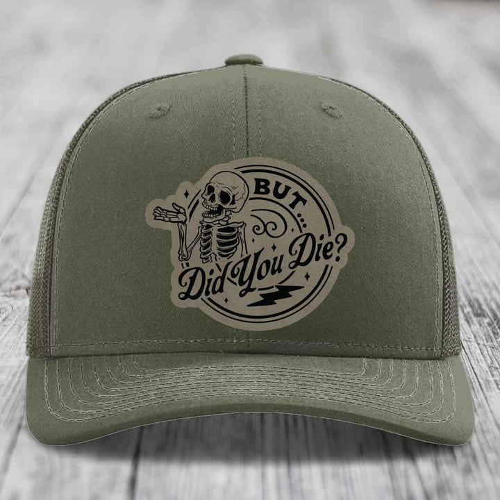 Olive green trucker hat with a circular skull patch that reads &