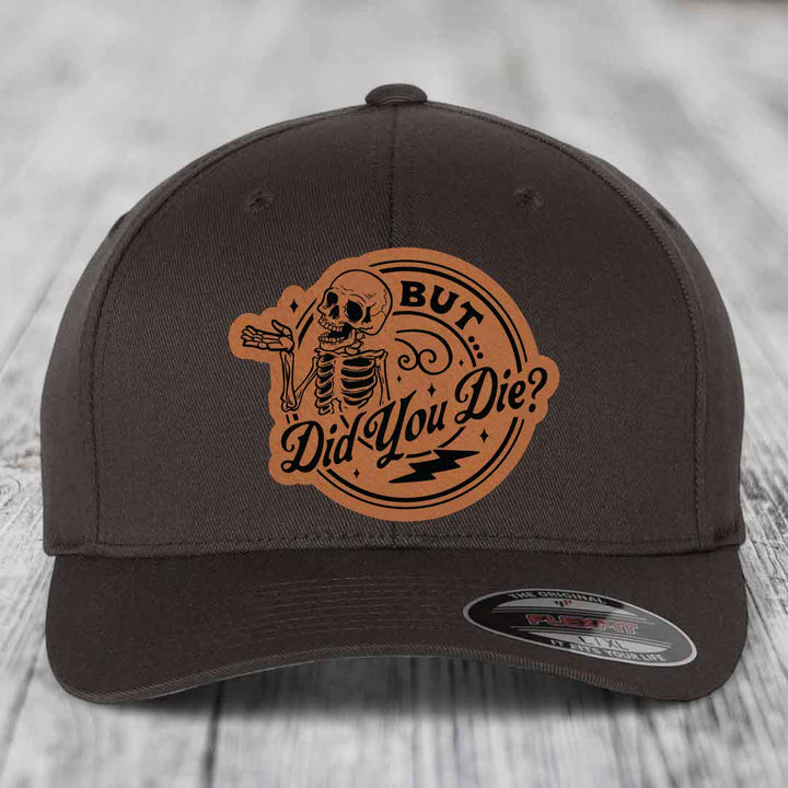 Dark brown Flexfit hat with a tan leatherette patch featuring a skeleton and the text &