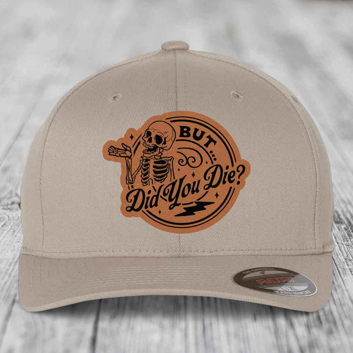 Beige baseball cap with brown leatherette patch featuring skeleton and text &
