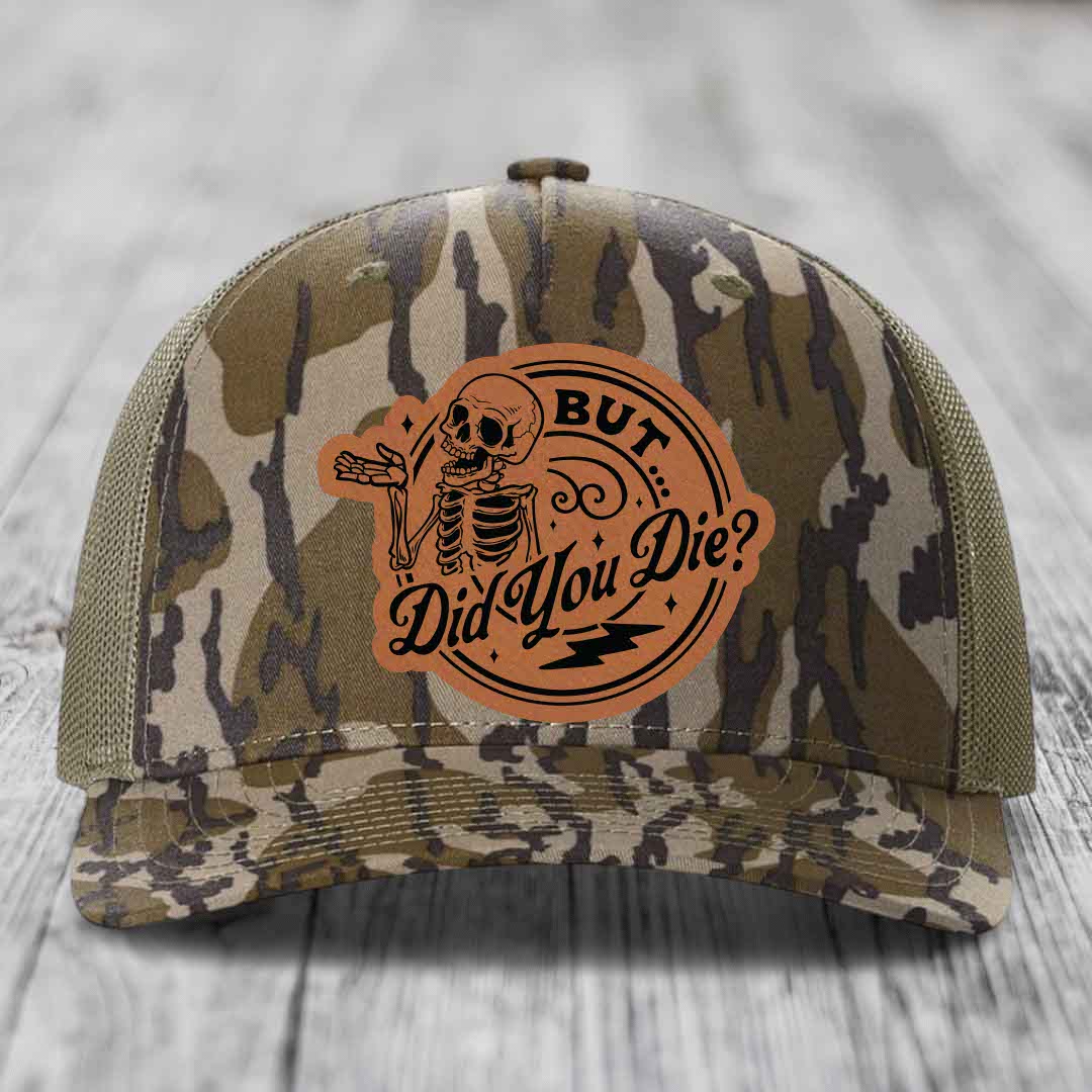 Camouflage trucker hat with orange leatherette patch featuring a skeleton and text &