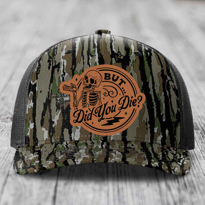 Camouflage trucker hat with brown leather patch featuring skeleton and text &