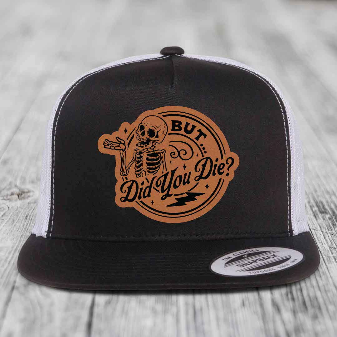 Black and white trucker hat with brown leather patch featuring skeleton and text &