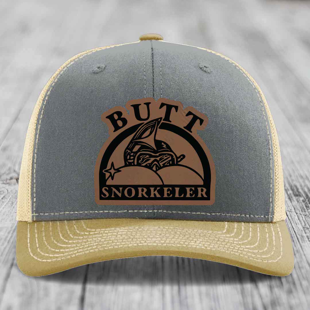 Grey and beige trucker hat with a brown leather patch reading &