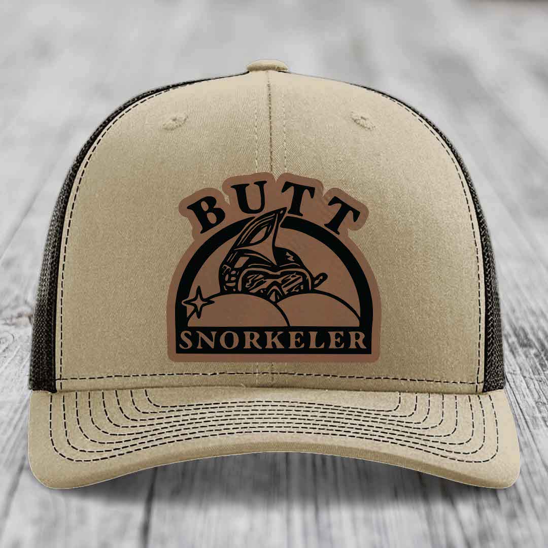 Beige trucker hat with brown leather patch reading &