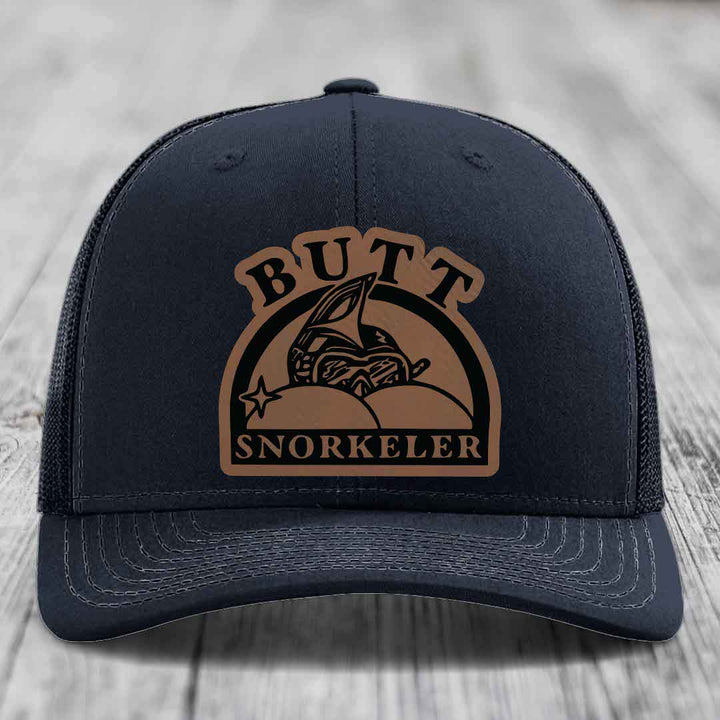 Black trucker hat with brown leather patch reading &