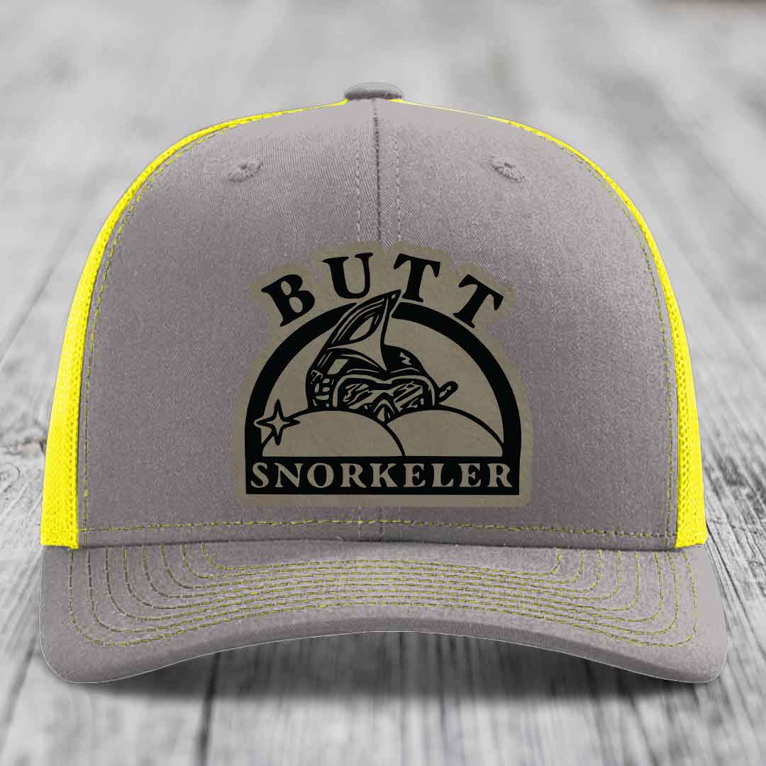 Grey trucker hat with yellow mesh and stitching, featuring a black &