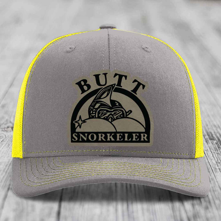 Grey trucker hat with yellow mesh and stitching, featuring a black &