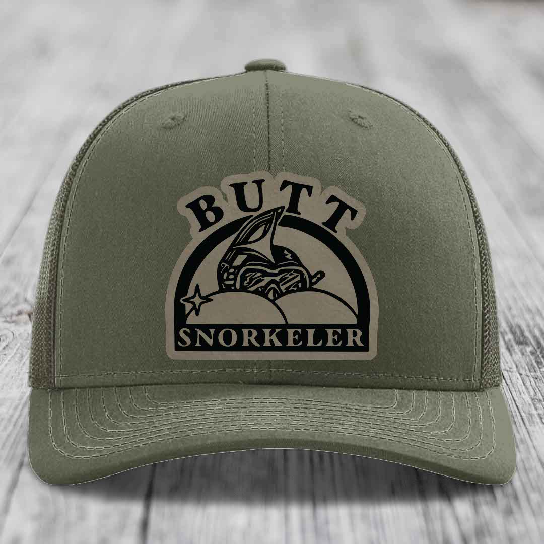 Olive green trucker hat with a beige leather patch reading &