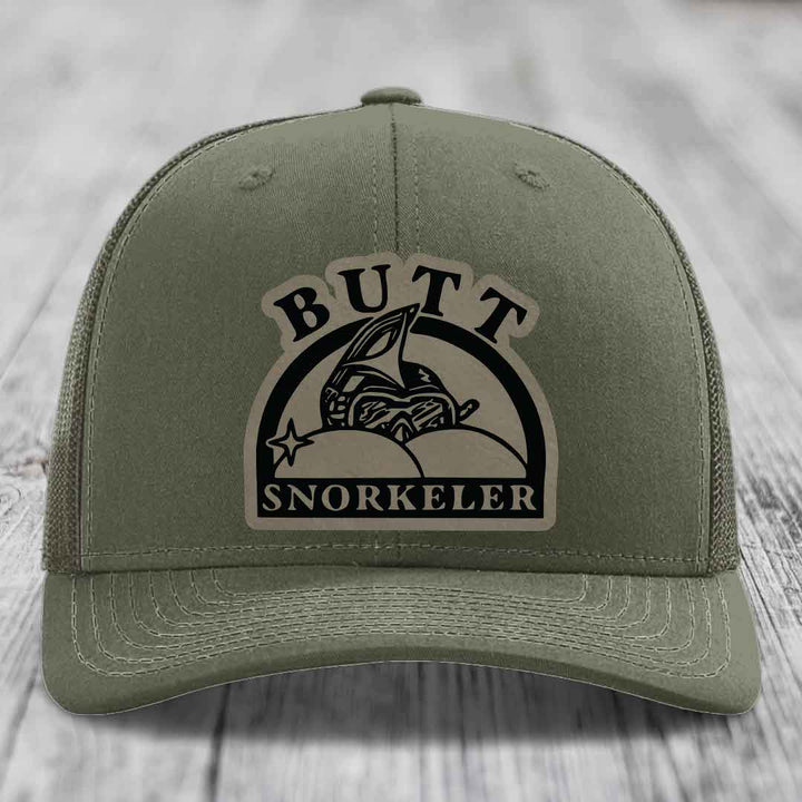 Olive green trucker hat with a beige leather patch reading &