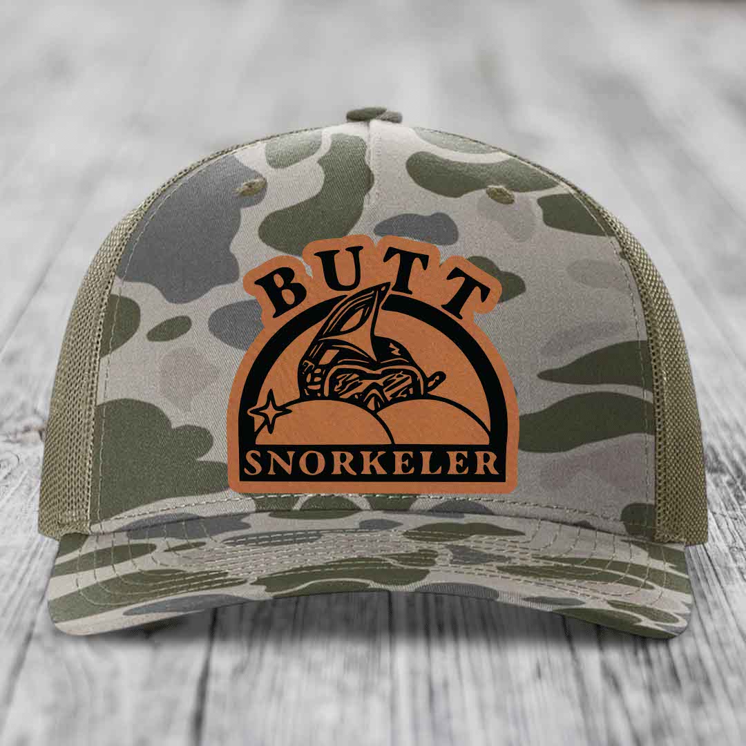 Camouflage trucker hat with brown leather patch reading &