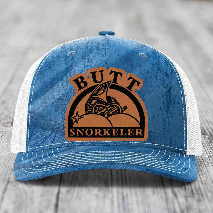 Blue and white trucker hat with brown leather patch reading &