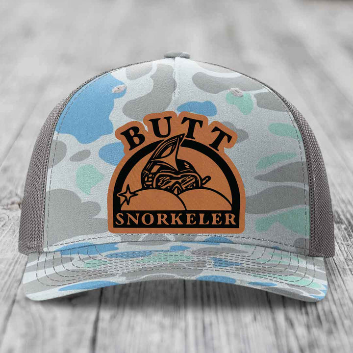 Camouflage trucker hat with brown leather patch reading &